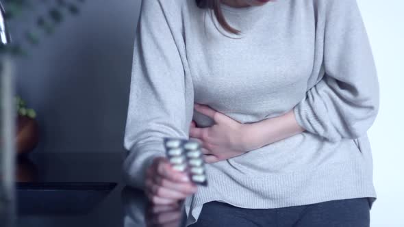 Woman Holding Medicine Against Stomachache