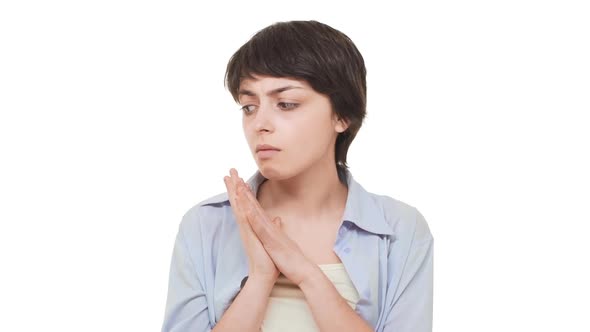 Young Nervous Caucasian Female with Short Haircut Rubbing Her Hands Standing at Loss Over White