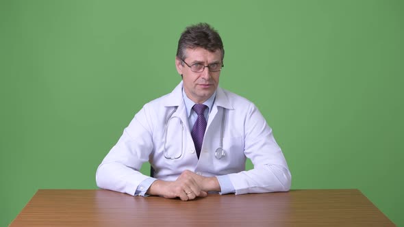 Mature Handsome Man Doctor Against Green Background