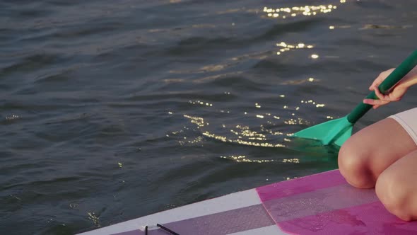 Close Up of Young Woman Floating on Colorful Sup Board