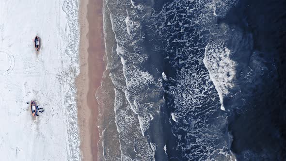 Aerial view of snowy fishing boats at winter Baltic Sea.