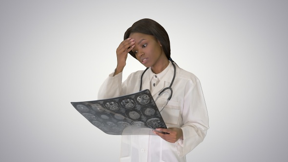 Young female doctor standing looking at X-ray of a brain