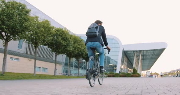 Office Worker with Backpack Riding a Bike on Cobbled Street