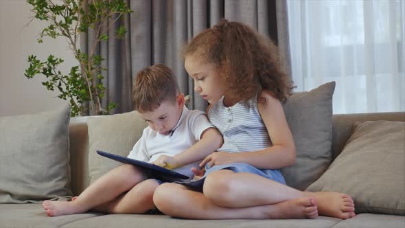 Cute Family and Daughter,sister-in-law a Nanny with Little Brother,looking at the Screen of a Tablet