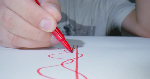 Person Draws Graph Line or Pattern for New Project Design with a Red Felttip Pen Front View Macro