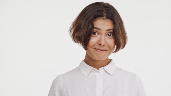 Young Beautiful Brunette East Asian Female in Shirt Shy Coy Nods Head Smiling on White Background in