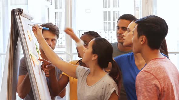 Business executives discussing over on whiteboard