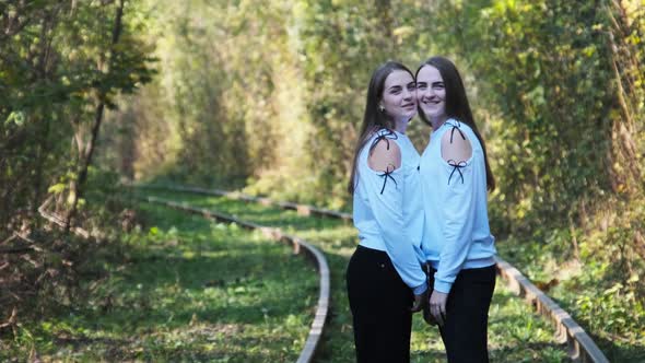 Smiling Young Twins Women Standing Together on Railroad