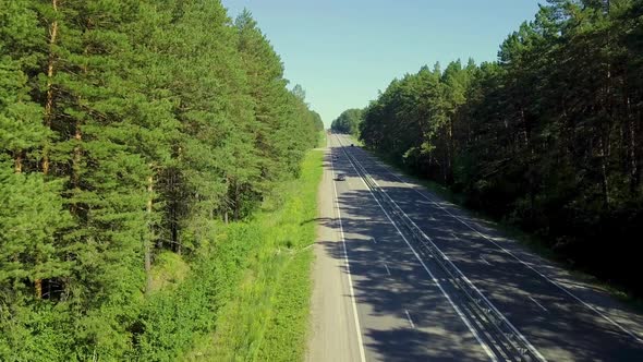 Aerial: Low Level Flying Over the Highway, Located in Dense Forest. On the Road Passing Cars 