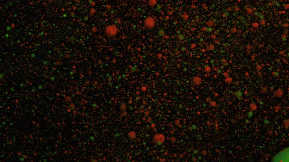 Orange and Green Volumetric Fluorescent Particles Move and Change on a Black Moving Background