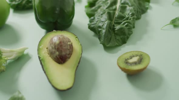 Video of fresh avocado, broccoli, green pepper, apple and green leaves on green background