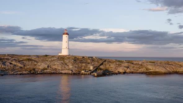 Lille Torungen Lighthouse By Sea Against Cloudy Sky During Sunset In Arendal, Norway - aerial drone