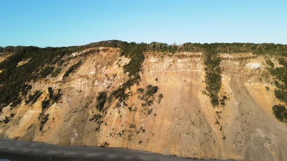 Revealing drone view of the constantly re-sculpt cliff lines of coloured sands at Rainbow Beach Quee