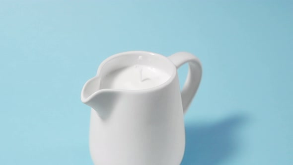 A Drop of Milk Drips Into a Full Milk Jug