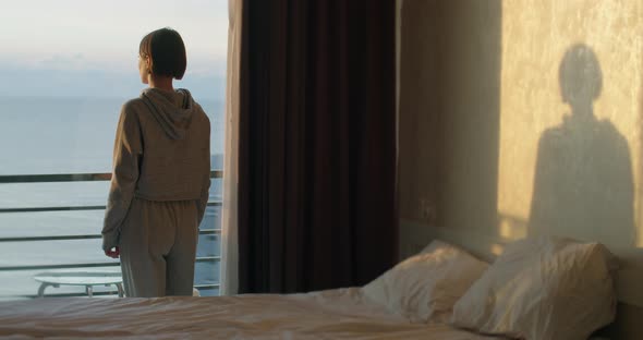 Young Girl Standing By Window and Enjoying Beautiful View