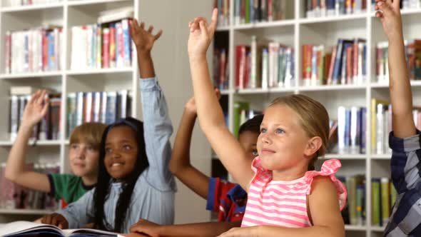 School kids raising hand in library