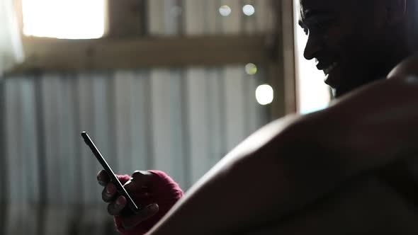 Boxer using smartphone in the gym