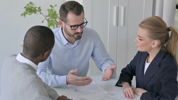 Businessman Explaining Papers to Male and Female Colleagues