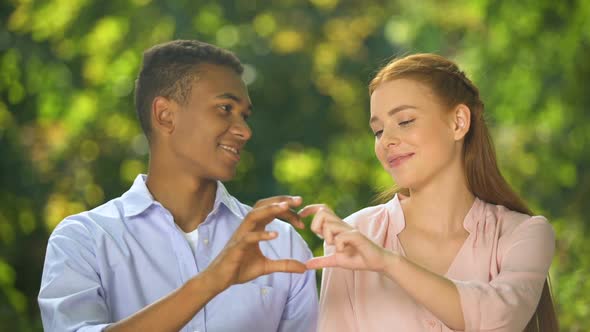 Multiethnic Couple Making Hand Heart Gesture Outdoor, First Relations, Love