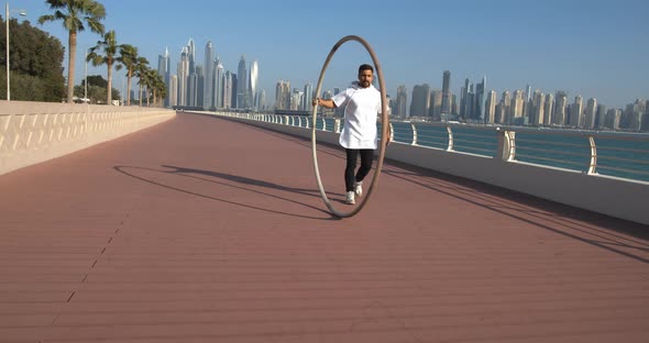 Sportsman is Walking and Rolling the Hoop on Palm Jumeirah in Dubai Gymnast
