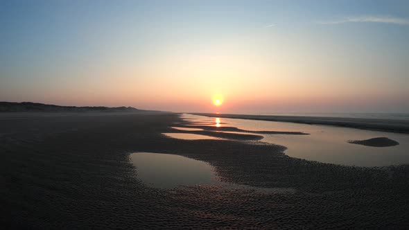 Aerial, tracking, drone shot over calm sea and patterns on the beach, on Langeoog island