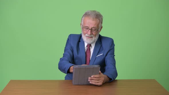 Handsome Senior Bearded Businessman Against Green Background