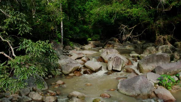 Drone flying towards dark jungle over creek, Samui, Thailand