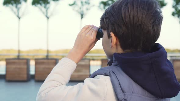 A Cute Boy Examines the Neighborhood Through Binoculars alt