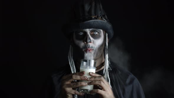 Creepy Man with Skeleton Makeup in Top-hat. Guy Looking at Camera, Drinks Milk From a Glass