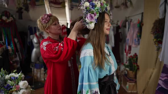Slim Beautiful Ukrainian Girl in Traditional Clothes Standing As Woman Putting on Head Wreath in