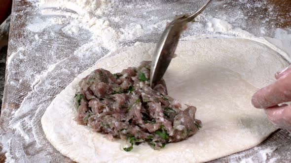 Chef make meat pies kutaba or chebureki, raw minced meat with onions and herbs filling dough.