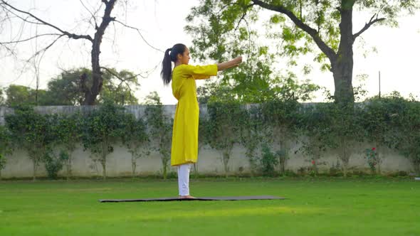 Indian woman doing Hand and wrist exercise or yoga in a park