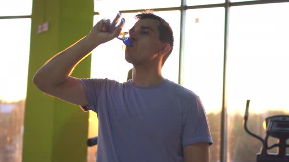 Sports Man Quenches Thirst After Training in a Stylish Gym