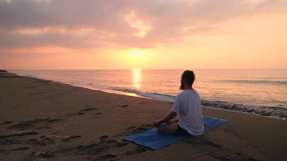 Man Sits in Lotus Position at Beach