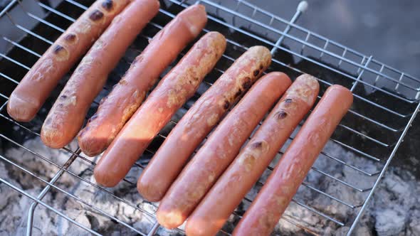 Closeup View of Tasty Sausages Grilling on Charcoal Grill Grate