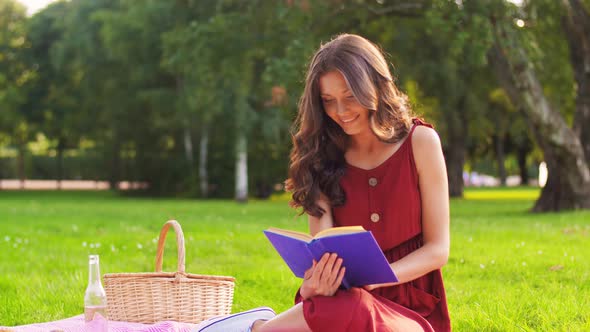 Happy Woman Reading Book at Picnic in Summer Park