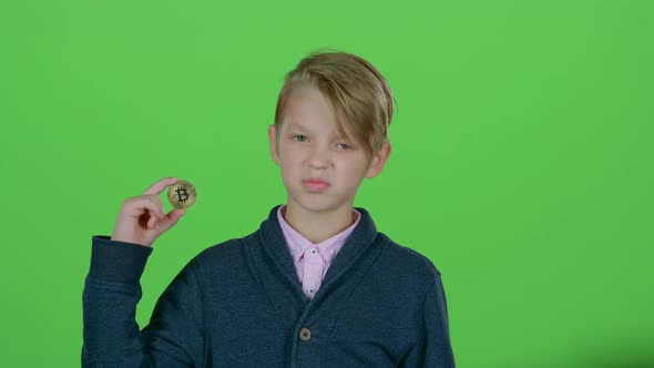 Child Boy Raises His Hand and Shows the Gold Bitcoin on a Green Screen