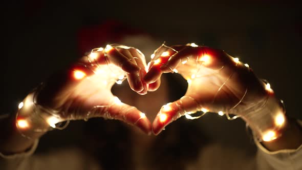 Woman Shows Heart Sign with Hands Decorated with Garlands