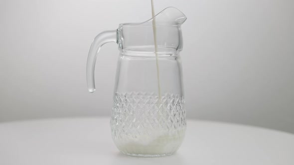 Closeup Glass Jug with White Healthful Milk Pouring in Slow Motion