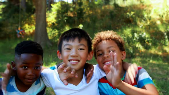 Portrait of happy kids waving hands in park