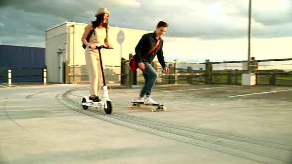 Young couple riding on longboard and electric scooter