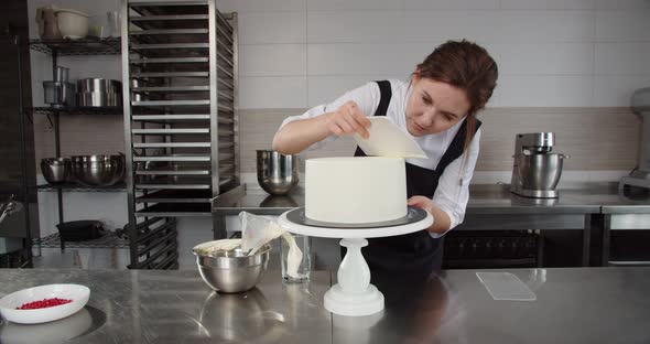 A Professional Confectioner Evenly Applies Cream to the Holiday Cake with a Special Pastry Spatula