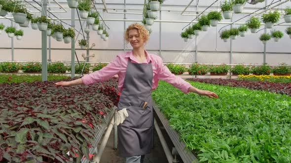 Happy Blonde Florist Gardener Enjoys Working in Her Greenhouse Walking Through Flower Saplings