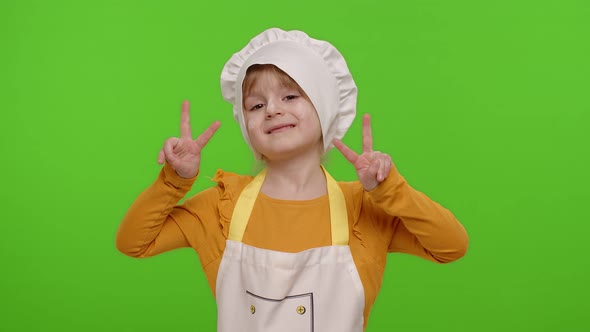 Little Child Girl Dressed Like Chef Cook Showing Victory Sign Hoping for Success and Win Peace