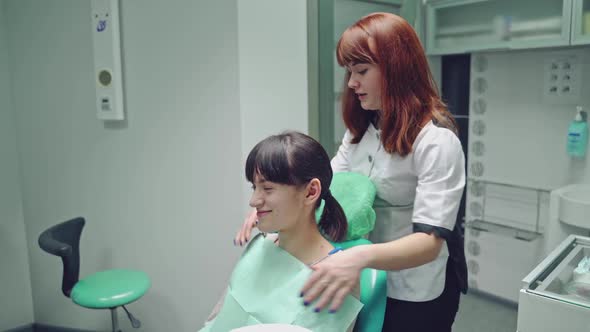 Dentist prepares the smiling patient for teeth treatment on the background of stomatology cabinet