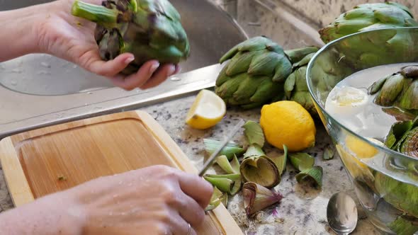 Woman Cleaning Heart of Artichokes with Spoon