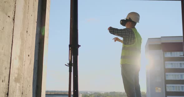 Engineer Builder Visualizes the Building Plan Standing on the Roof of the Building at Sunset Stands