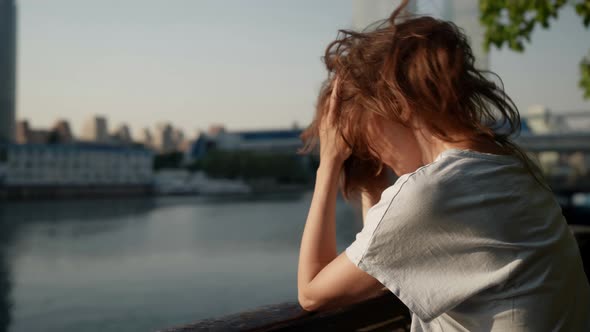 the Brunette Leans on the Fence of the City Embankment and Touches Hair Against the Background of