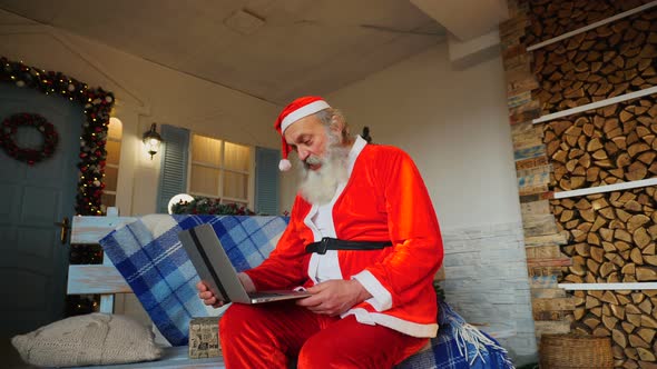 Jocund Father Christmas Talking with Video By Laptop. 