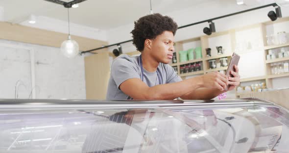 Animation of happy biracial waiter using tablet at coffee shop